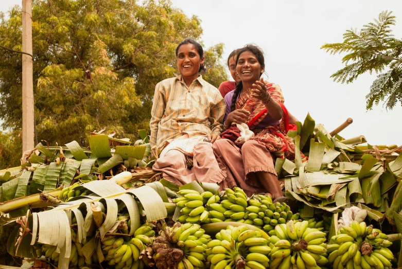 a couple of people sitting on top of a pile of bananas, tribals, uncrop, portrait image