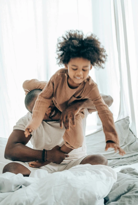 a man and a little girl playing on a bed, pexels contest winner, wearing a tee shirt and combats, light skinned african young girl, swirling around, brown clothes