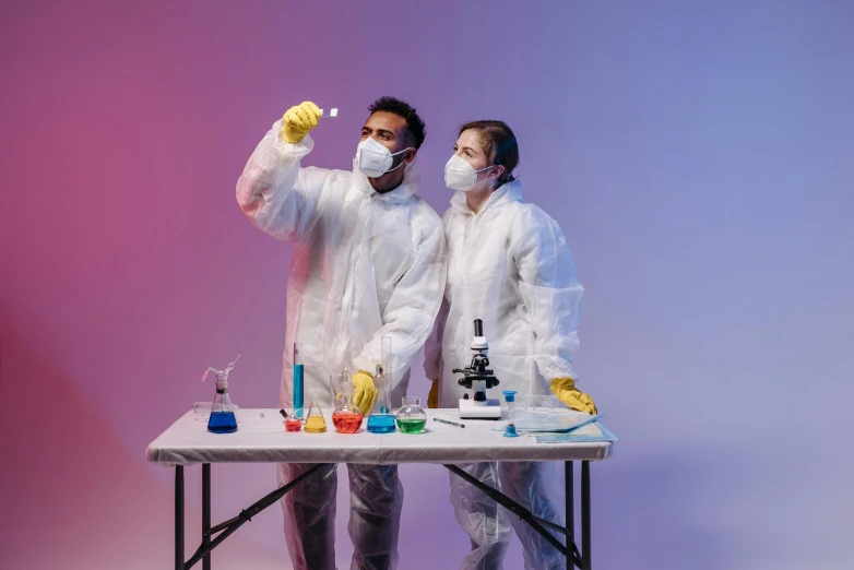 a couple of people that are standing in front of a table, pexels contest winner, analytical art, staff wearing hazmat suits, wearing a labcoat, 🚀🌈🤩, studio photo