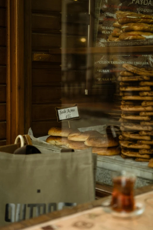 a man sitting at a table in front of a bakery, a picture, by Jan Tengnagel, pexels contest winner, art nouveau, sliced bread in slots, window in foreground, cookies, medium close-up shot