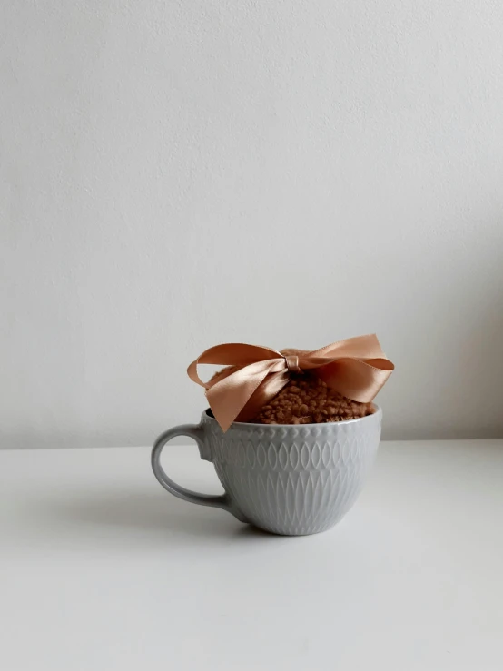 a close up of a cup with a cookie in it, by Eleanor Best, textured base ; product photos, ribbon, jakarta, grey