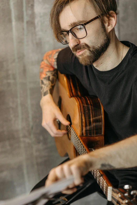 a man with a beard playing a guitar, inspired by Ásgrímur Jónsson, pexels contest winner, modernism, wearing black rimmed glasses, promotional image, handsome man, half length