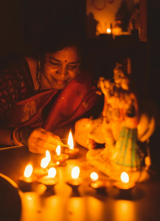 a woman lighting candles in a dark room, by Max Dauthendey, pexels contest winner, happening, ganesha, a still of a happy, profile image, video still