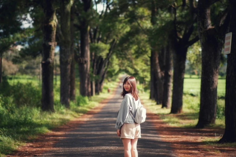 a little girl standing in the middle of a road, by Ai-Mitsu, unsplash, visual art, under the soft shadow of a tree, background image, japan rural travel, handsome girl