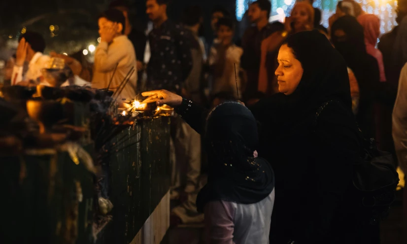 a woman lighting candles in front of a crowd of people, hurufiyya, fan favorite, profile image, muslim, family photo