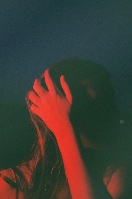 a woman covering her face with her hands, an album cover, inspired by Elsa Bleda, unsplash, dark blue and red, injured, red monochrome, facepalm