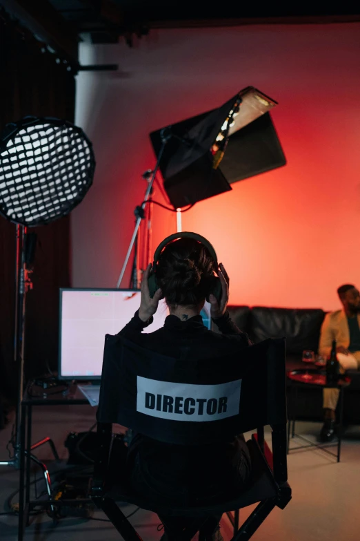 a person sitting in a chair in front of a camera, facing away from the camera, studio lights, top production, studio recording