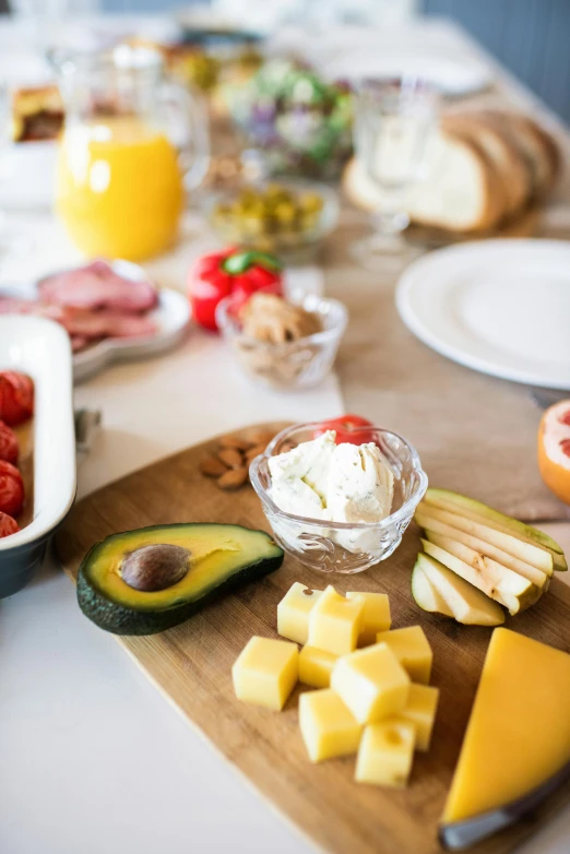 a wooden cutting board sitting on top of a table, pexels, breakfast buffet, avocado and cheddar, plates of fruit, at home