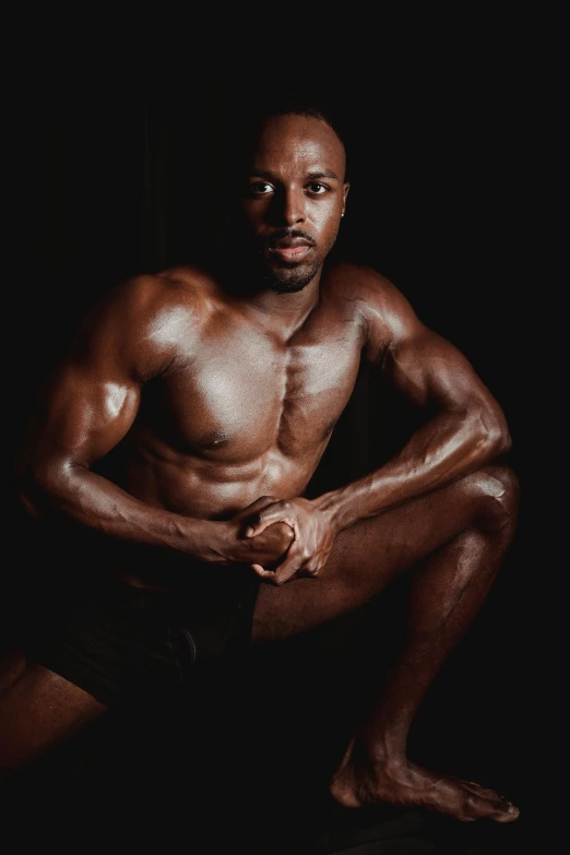 a man that is sitting down in the dark, an album cover, by Jessie Alexandra Dick, pexels contest winner, renaissance, athletic body build, black main color, covered in oil, chris evans as a bodybuilder