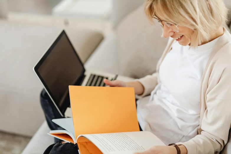 a woman sitting on a couch reading a book, a cartoon, trending on pexels, typing on laptop, school curriculum expert, a blond, close up portrait shot