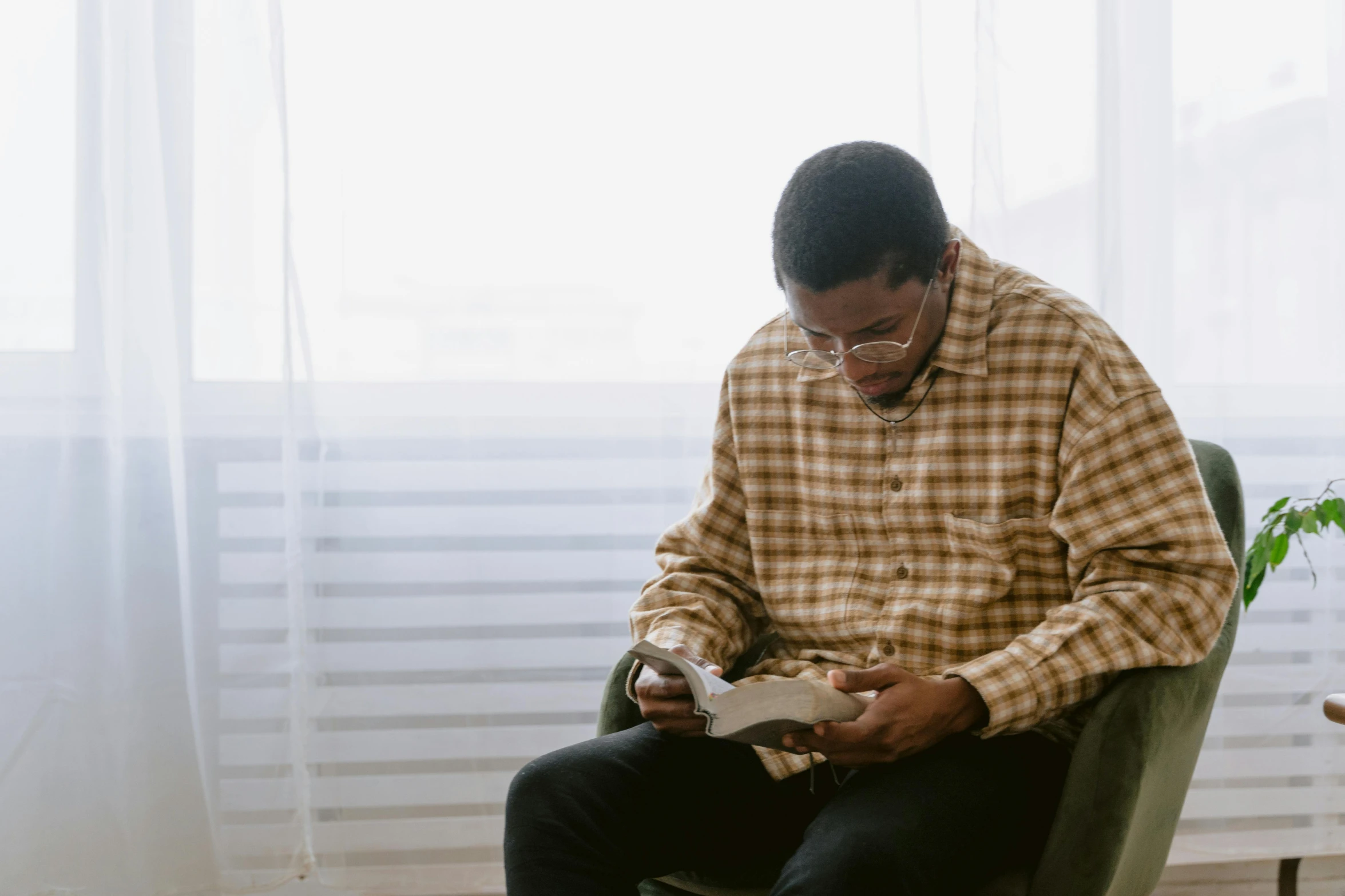 a man sitting in a chair reading a book, pexels contest winner, wearing a shirt, jemal shabazz, trying to study, riyahd cassiem