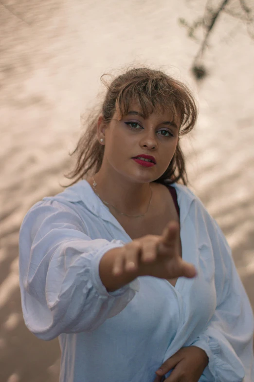 a woman standing in front of a body of water, an album cover, inspired by Márta Lacza, unsplash, renaissance, wearing a white button up shirt, pointing at the camera, fat latin woman dancing, tense look