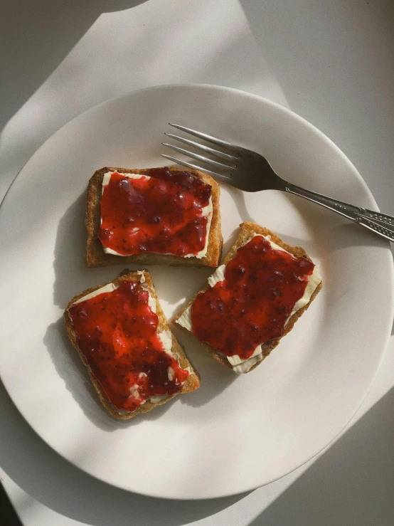 a white plate topped with four pieces of toast, by Ben Zoeller, reddit, in crimson red, jelly, high angle view, low quality photo