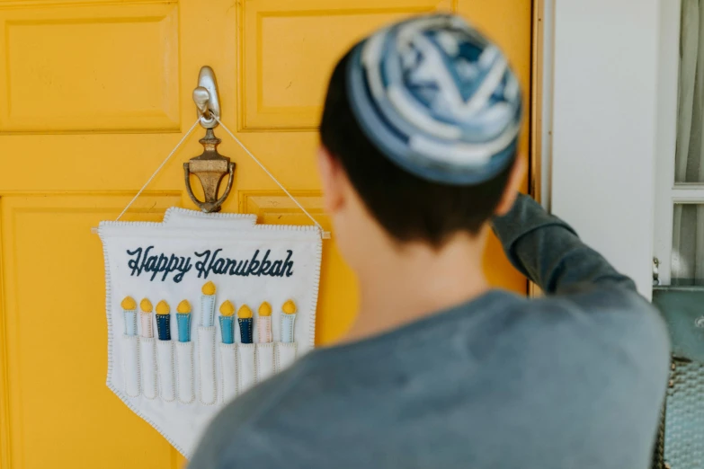 a man standing in front of a yellow door, by Julia Pishtar, trending on unsplash, hurufiyya, hebrew, decorations, holding a white flag, holiday