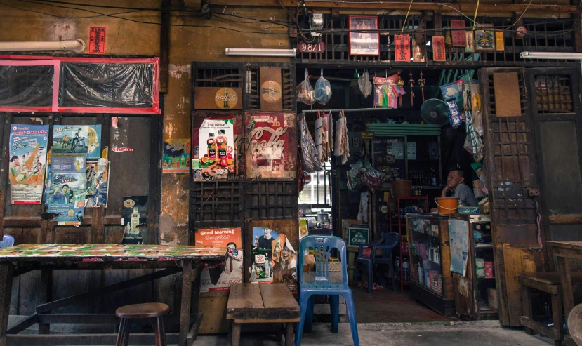 a man sitting at a table in front of a store, pexels contest winner, maximalism, patiphan sottiwilaiphong, local bar, back alley, panoramic shot