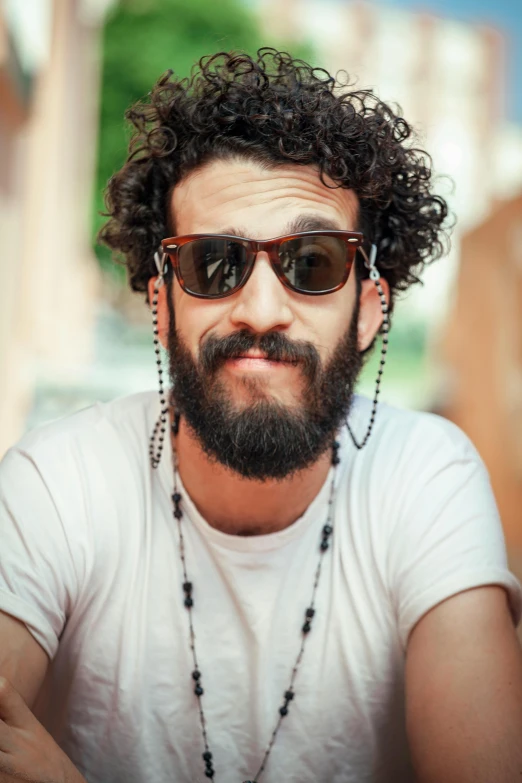 a man with a beard and sunglasses posing for a picture, curly haired, amr elshamy, heterochromia, trending on imagestation