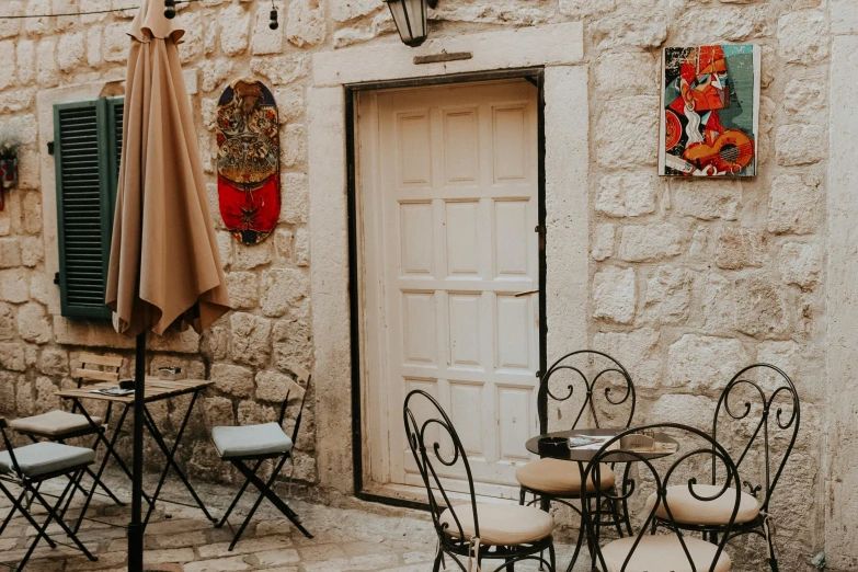 a stone building with tables and chairs in front of it, pexels contest winner, doorway, background image, brown, mixed art