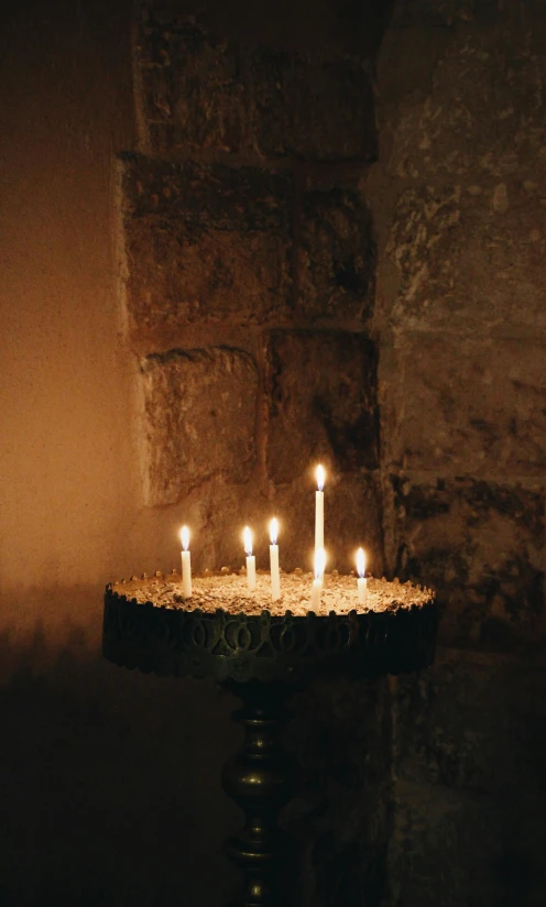 a group of lit candles sitting on top of a table, inspired by Elsa Bleda, romanesque, in a medieval crypt, baptism, day light, sparkling