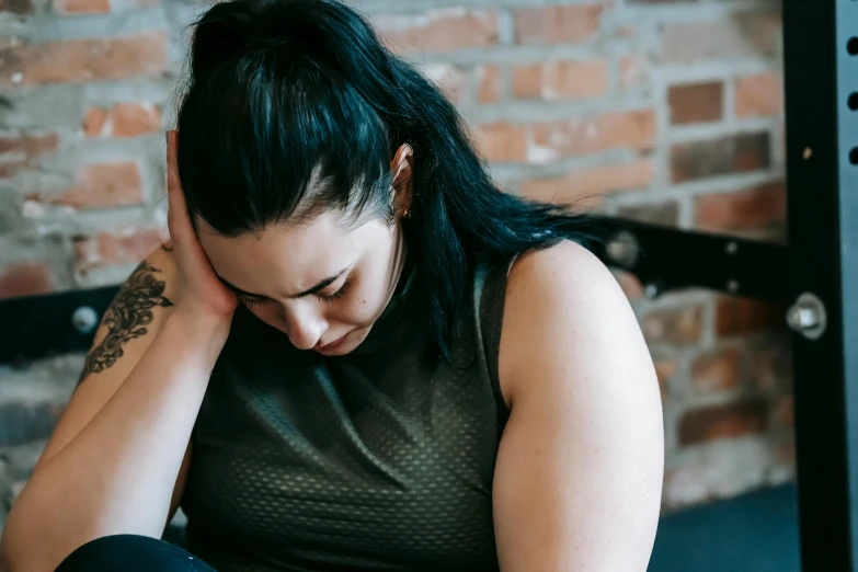 a woman sitting on a bench with her head in her hands, trending on pexels, overweight, photograph of a sleeve tattoo, disappointed, swollen muscles