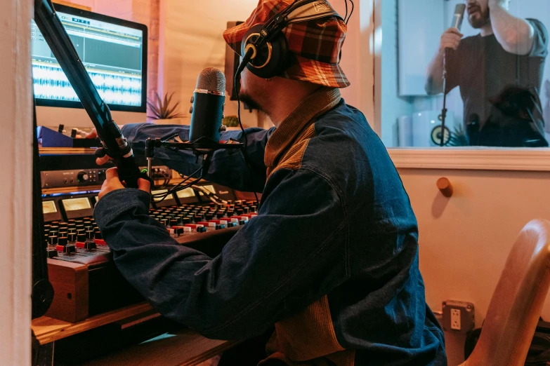 a man sitting at a desk in front of a computer, an album cover, pexels, rapping into microphone, headphones on head, studio orange, thumbnail