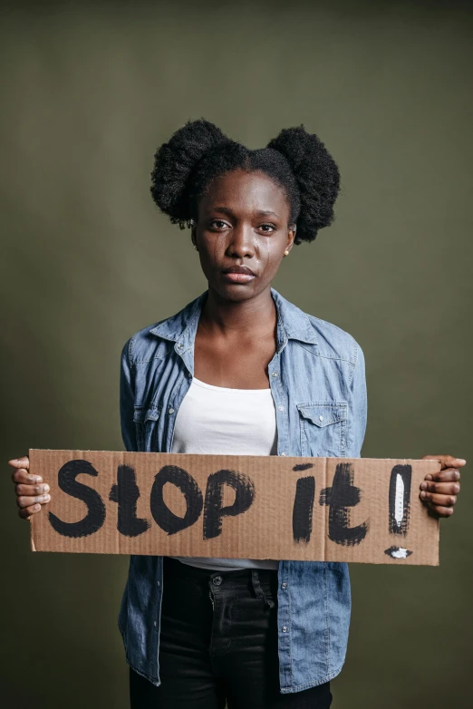 a woman holding a sign that says stop it, by Stokely Webster, trending on pexels, panel of black, teenage no, brown, 256435456k film