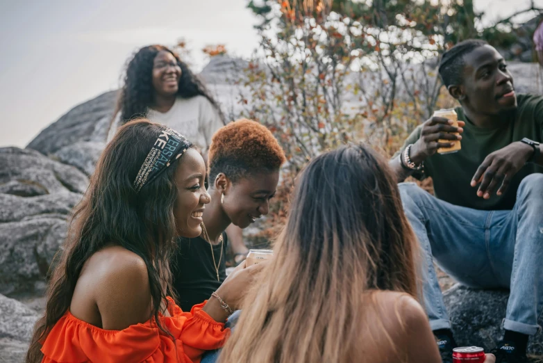 a group of people sitting on top of a rock, trending on pexels, happening, long afro hair, at a birthday party, warm coloured, profile image