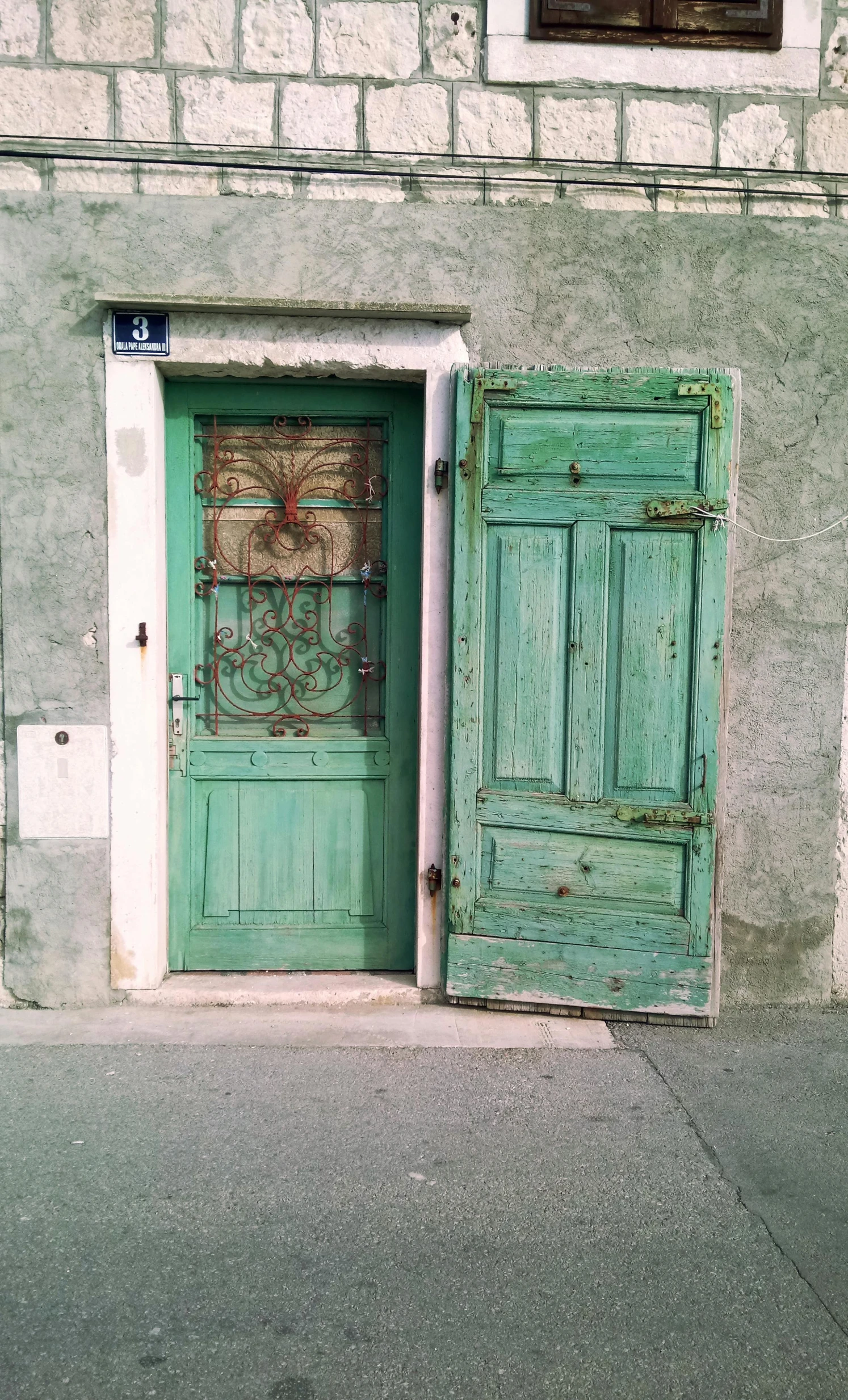 a couple of green doors sitting on the side of a building, by Adam Szentpétery, renaissance, split near the left, verdigris, wood door, whitewashed buildings