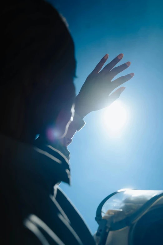 a person holding their hand up to the sun, happening, contemplative, sun shines down on the car, window light, clear blue skies