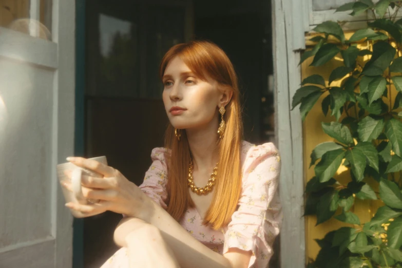 a woman sitting on a porch holding a cup, inspired by Elsa Bleda, trending on pexels, magic realism, bryce dallas howard, wes anderson and gucci, girl with a pearl earringl, petra collins and mc. escher