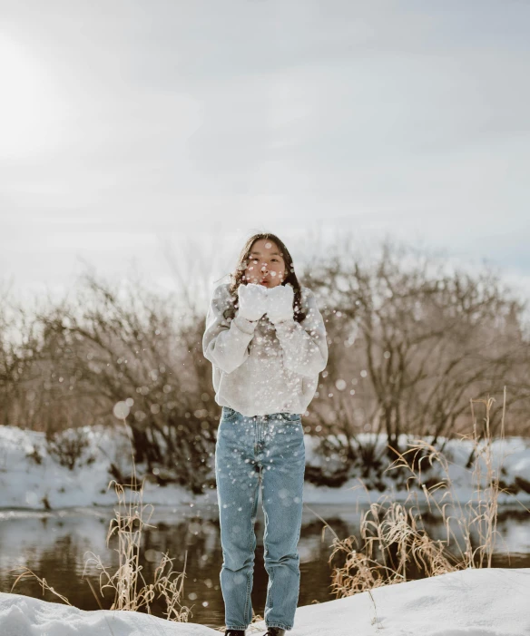 a woman standing on top of a snow covered field, white shirt and jeans, unsplash photography, happy kid, standing in a pond