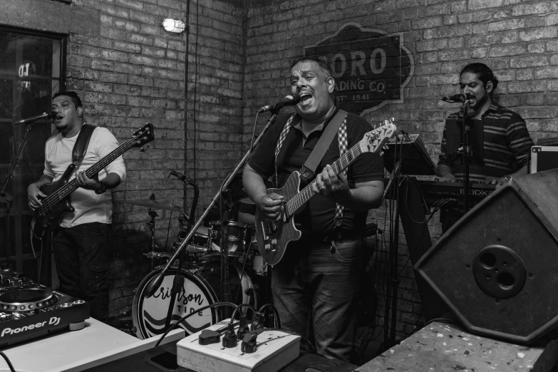 a band performing in front of a brick wall, by Robbie Trevino, blues, the argo, hero, from wheaton illinois