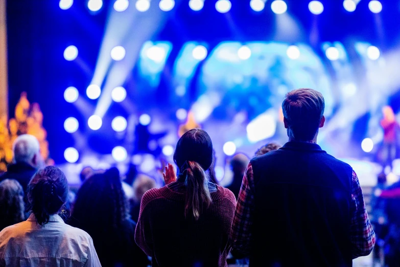 a group of people standing in front of a stage, pexels, happening, blue light accents, listening to godly music, looking from behind, instagram post