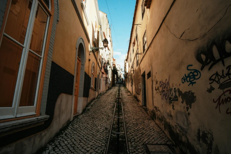 a narrow street with a train track going through it, pexels contest winner, graffiti, portugal, colonial era street, multiple stories, youtube thumbnail