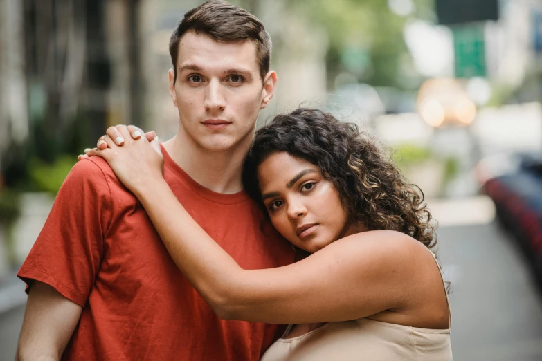 a man and a woman standing next to each other, a portrait, by Adam Marczyński, pexels, mixed-race woman, slightly red, promotional image, looking her shoulder