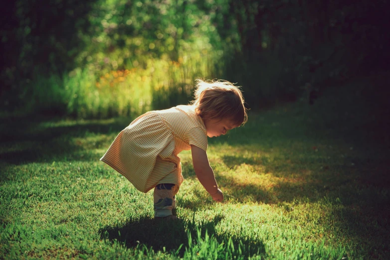 a little girl standing on top of a lush green field, pexels contest winner, dappled light, crouching, retro effect, walking at the garden