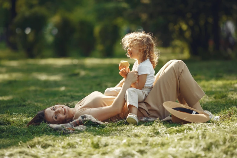 a woman and a little girl laying in the grass, having a picnic, high quality product image”, manuka, thumbnail