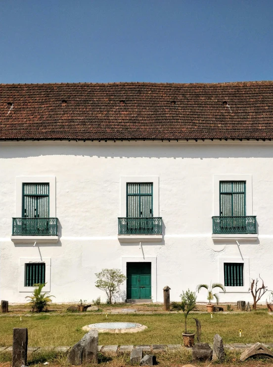 a white building with a green door and windows, inspired by Francis Souza, pexels contest winner, colonial expedition, lawn, elevation view, square