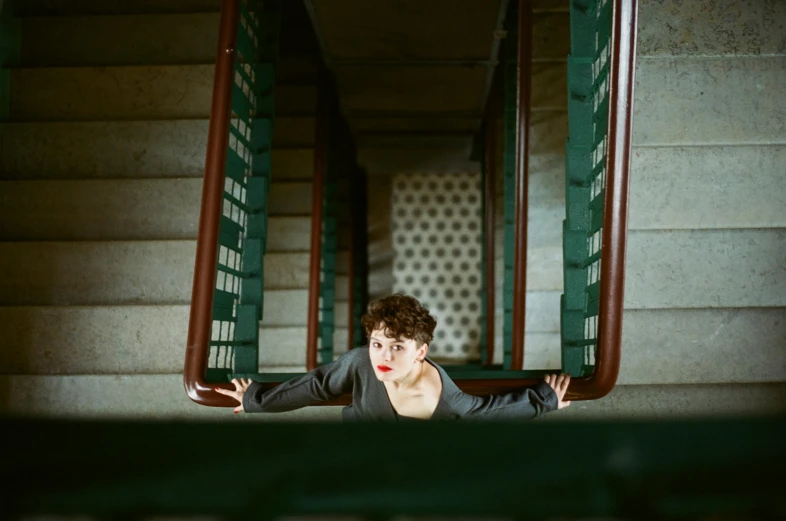 a woman standing at the bottom of a flight of stairs, an album cover, inspired by Elsa Bleda, pexels contest winner, bauhaus, sophia lillis, desperate pose, sean young, square