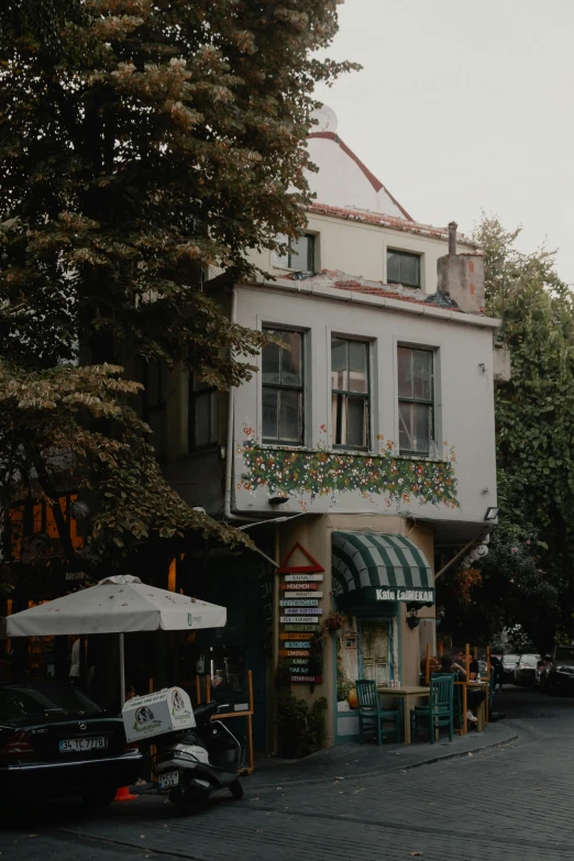a large white building sitting on the side of a road, a colorized photo, pexels contest winner, art nouveau, cozy cafe background, fallout style istanbul, background image, ivy's