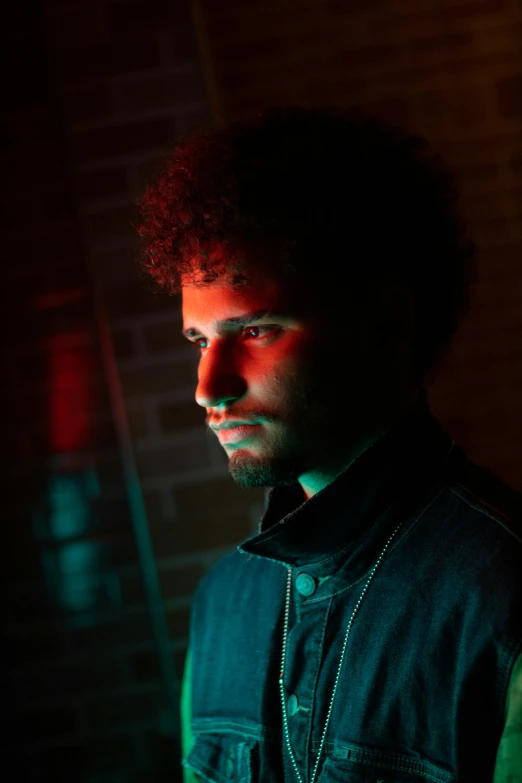 a man standing in front of a brick wall, an album cover, pexels contest winner, serial art, glowing red eyes, young spanish man, studio backlight, with afro