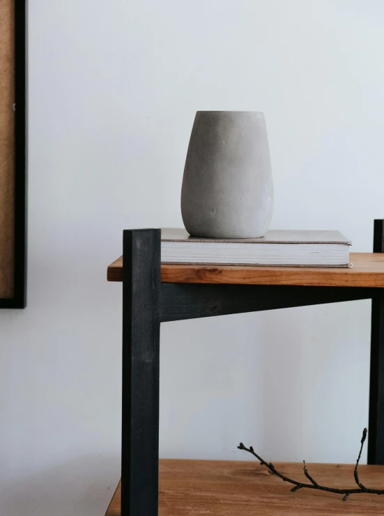 a white vase sitting on top of a wooden table, concrete art, in gunmetal grey, dwell, over-shoulder shot, tall