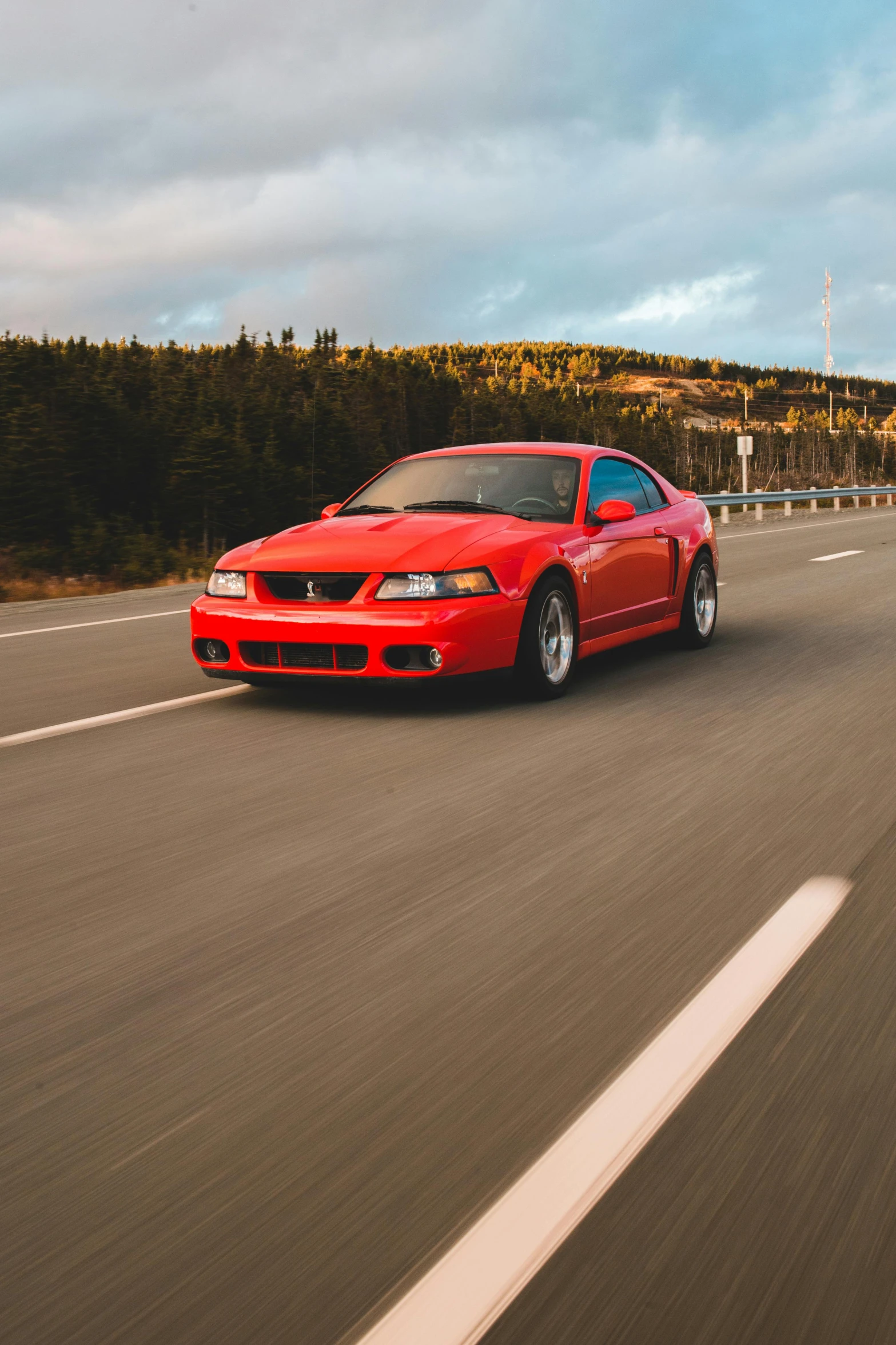 a red car driving down a highway next to a forest, mustang, profile image, single subject, f/1.4