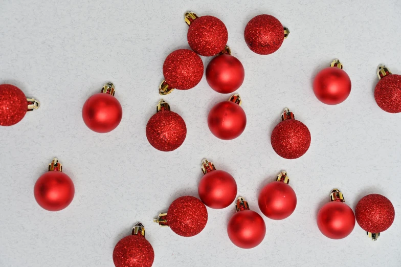 a number of red christmas ornaments on a white surface, a stipple, pexels, mini model, on grey background, laura watson, all around