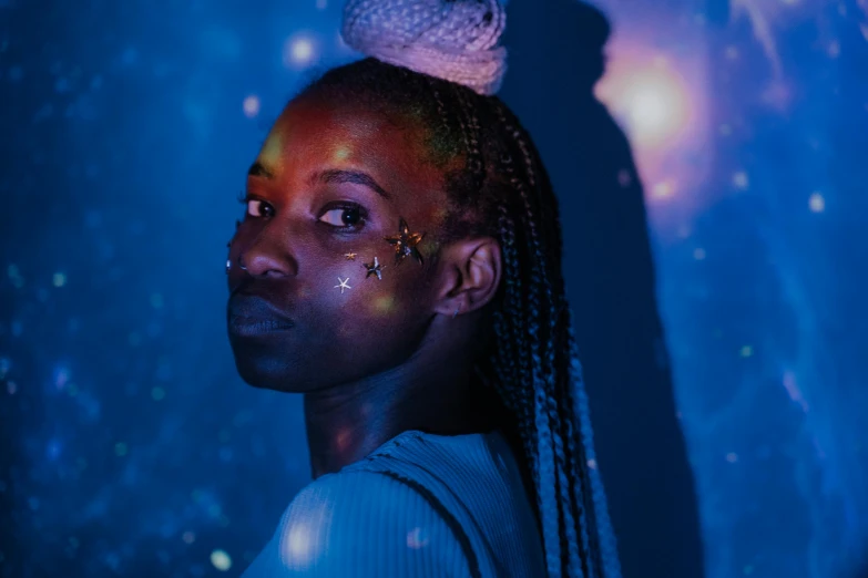 a close up of a person with glitter on their face, an album cover, pexels contest winner, afrofuturism, blue nebula, lights on, wearing a dress made of stars, space molly