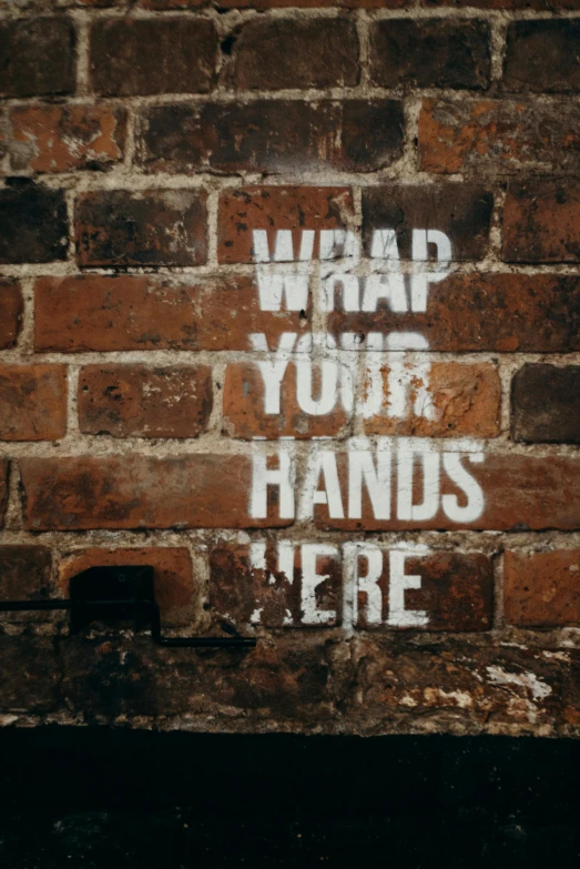 a brick wall with the words what what your hands here written on it, an album cover, by Ian Hamilton Finlay, pexels, graffiti, square, hand wraps, m