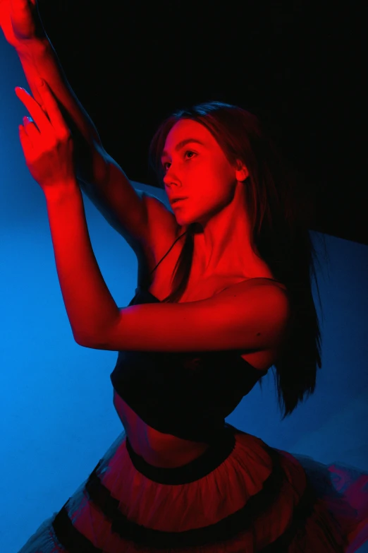 a woman standing in front of a red light, arabesque, blue and red lighting, doing a hot majestic pose, in a black room, stretch