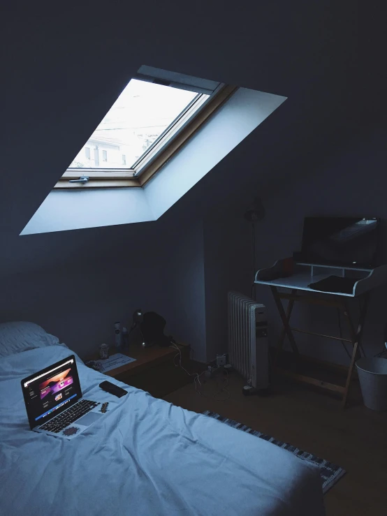 a laptop computer sitting on top of a bed, a polaroid photo, inspired by Elsa Bleda, light and space, skylights, overcast mood, in an attic, trending on vsco