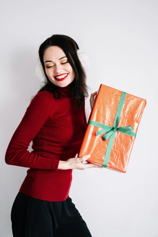 a woman in a red shirt holding a present, pexels contest winner, wearing an orange jumpsuit, alexandria ocasio cortez, brunette woman, minimalissimo