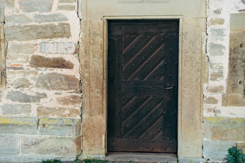 a black fire hydrant sitting in front of a door, inspired by Károly Markó the Elder, unsplash, romanesque, wood door, 1 5 6 6, john pawson, brown