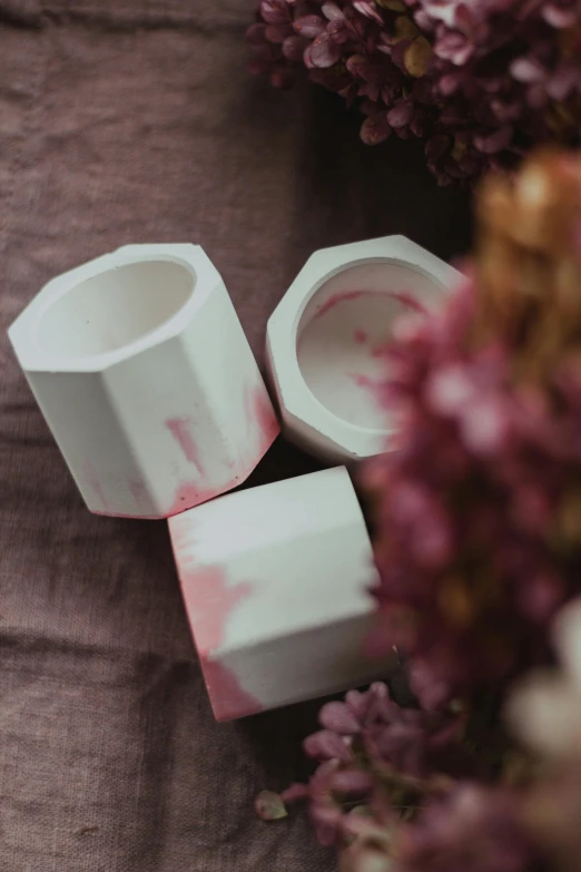 a couple of cups sitting on top of a table, a marble sculpture, inspired by Hendrik Gerritsz Pot, unsplash, process art, petal pink gradient scheme, six sided, close-up product photo, with soft bushes